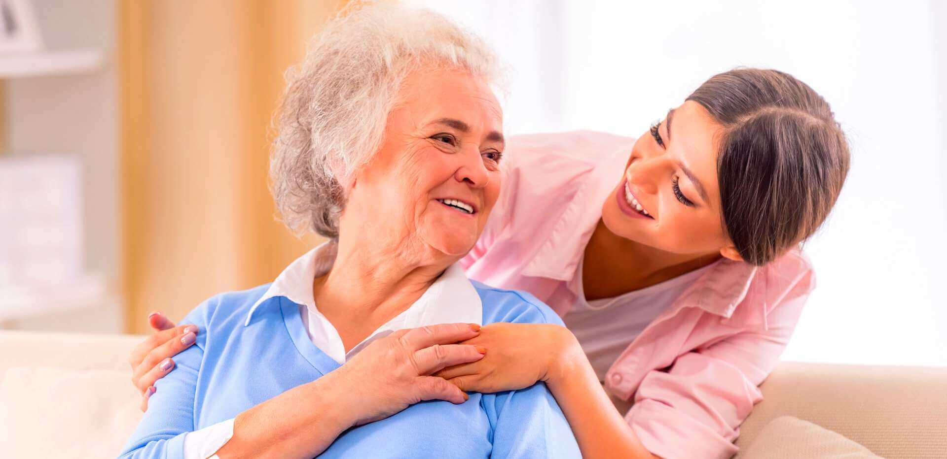 An older woman smiling with a supportive companion at home